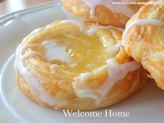 three glazed pastries on a plate with the words welcome home written in white lettering