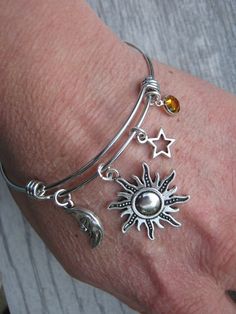 Hand created and personalized with love, this nnature inspired expandable bangle bracelet features lead/nickel free: antiqued silver tone Sun, Crescent Moon and Star pendant charms with genuine Swarovski birthstone crystal on an adjustable stainless steel bangle bracelet. Bracelet measures 60/65mm in diameter and fits 6-8.5 inch wrist size. Please note you will need to expand this bracelet over your hand. This bracelet is Ready to Ship. CHOOSE your birthstone crystal at checkout (shown in 3rd ph Adjustable Celestial Charms Jewelry, Adjustable Sun And Moon Design Bracelets As Gift, Adjustable Personalized Celestial Jewelry, Celestial Adjustable Charm Bracelet Gift, Adjustable Celestial Personalized Jewelry, Silver Celestial Bangle Jewelry, Celestial Silver Bangle Jewelry, Celestial Silver Metal Bracelets, Celestial Style Silver Metal Bracelets