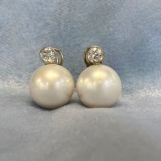 This beautiful pair of earrings features two round south-sea pearls with high luster. Two old European cut diamonds are bezel set above the pearl with a total approximate diamond weight of 1.50 carats. These earrings are handcrafted in platinum with gold clip-backs. The measurements of the pearls are 17mm each. A matching pair of cultured pearls and this size and luster are rare. ✦ EARRING SPECIFICATIONS: Ring Material: Platinum Stones: Diamond, Pearl ✦ WHAT COMES IN YOUR SHIPMENT: - Your Earrin White Round Clip-on Diamond Earrings, Classic Round Pearl Clip-on Earrings, White Clip-on Pearl Earrings Fine Jewelry, Wedding Pearl Earrings Round Shape, Pearl Clip-on Earrings, Wedding Pearl Earrings With 17 Jewels, Classic Round Pearl Drop Clip-on Earrings, Classic Round Clip-on Earrings With Pearl Drop, Wedding Round Pearl Earrings