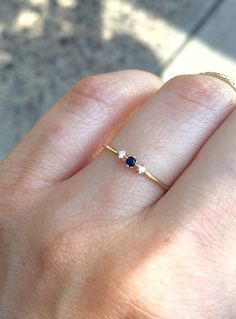 a woman's hand with a gold ring and two blue stones on it,