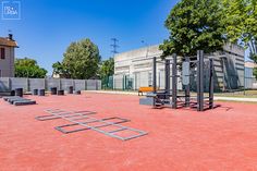 an empty playground with benches and swings in front of a building on a sunny day