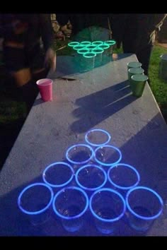 some cups are sitting on a table with neon lights