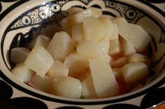 a bowl filled with sliced onions on top of a table