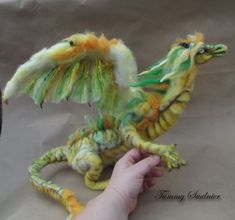 a hand is holding a yellow and green dragon