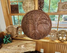 wooden carvings are hanging from the ceiling in front of a window with wood trimmings