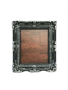 an old black frame on a white wall with a wooden floor in the middle and silver trimmings