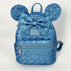 Minnie's Singing The Blues With Her Latest Mouse-Eared Mini Backpack. This Sparkling, Sequined Creation By Loungefly Is Fronted By A Beautiful Matching Bow, All In A Shade Of Hydrangea Blue. * Sequined Body, Padded Ears And Bow * Simulated Leather Grain Trims, Back, Handle And Shoulder Straps * Double Zip Main Compartment * Front Zip Pocket * Loungefly Logo Metal Pulls * Two Side Slip Pockets * Top Carry Handle * Hydrangea And Mickey Mouse Icon Print Lining * Adjustable Padded Shoulder Straps * Cute Blue Backpack With Zipper Closure, Blue Backpack For Disney Trips With Adjustable Strap, Cute Blue Backpack With Adjustable Strap, Blue Backpack With Adjustable Strap For Disney Trips, Disney Blue Standard Backpack, Blue Backpack For Disney Fan Events, Disney Blue Bags With Zipper Closure, Blue Disney Backpack With Zipper Closure, Blue Disney Bags With Zipper Closure