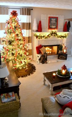 a living room decorated for christmas with a lit tree in the corner and candles on the coffee table