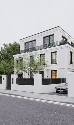 a car parked in front of a white building with black balconies on the windows