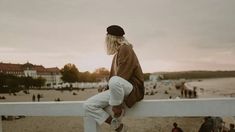 a person sitting on a rail looking at the beach