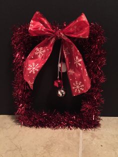 a red bow with snowflakes hanging from it's side on a black wall