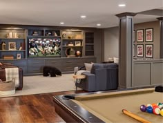 a living room filled with furniture and a pool table in front of a tv mounted on the wall