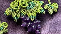 some green and purple beads are laying next to each other on a cloth surface with leaves