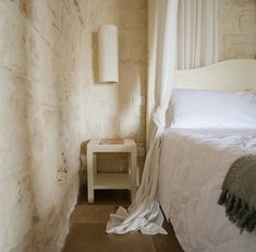 a white bed sitting next to a small table with a lamp on top of it