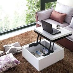 a coffee table with a laptop on it in front of a couch and windowsill