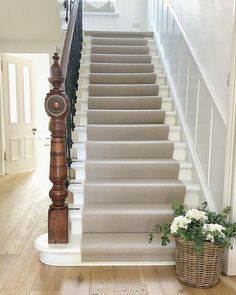 the stairs are lined with white flowers and wood balustiers, along with a basket full of greenery