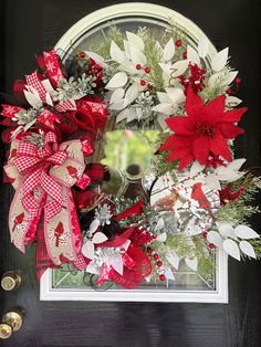 a wreath with poinsettis and greenery on the front door