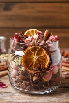 a glass jar filled with orange slices, cinnamons and other spices on top of a wooden table