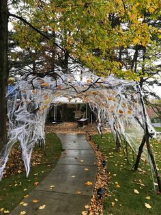 an outdoor walkway decorated with white plastic wrap and orange leaves on the ground next to a tree