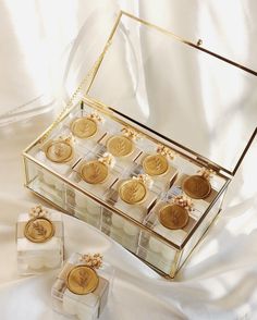 a glass box filled with gold coins on top of a white cloth covered tablecloth