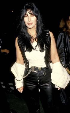 a woman with black hair wearing leather pants and a white shirt is posing for the camera