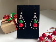 Add some holiday cheer with these unique and elegant red and green framed jingle bell earrings with silver-plated non-nickel ear wires and silicone backers. The center beads swing freely in the silver plated frame making them a fun accessory. This item will come packaged in a gift box. I'm happy to include a message for the recipient.   All items are designed and handmade to order by me.  Requests for customizations are welcomed. I will do my best to have your order in the mail within 24 hours. Thank you for supporting my small business! Red Holiday Earrings With Ear Wire, Holiday Red Ear Wire Earrings, Red Ear Wire Earrings For Holiday, Festive Green Nickel-free Earrings, Red Dangle Earrings For Holiday, Red Dangle Earrings For Holidays, Red Ear Wire Jewelry For Holidays, Nickel Free Christmas Drop Earrings, Red Holiday Earrings