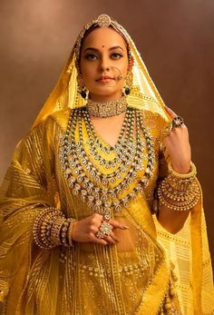 a woman in a yellow outfit with jewelry on her head and hands behind her back