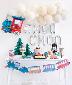 a train themed birthday party with balloons, cake and decorations on a white table top