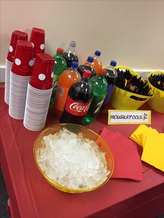 a table topped with lots of soda bottles next to bowls of ice and paper napkins