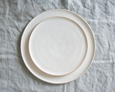 an empty white plate sitting on top of a cloth covered tablecloth with the edge of it