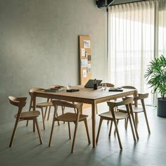 a dining room table with chairs and a potted plant in the corner next to it