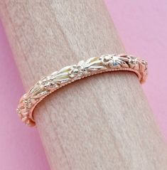 a close up of a wedding ring on a wooden surface with a pink wall in the background