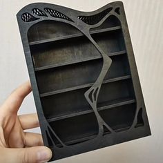 a person holding up a black book case with holes in the front and bottom section