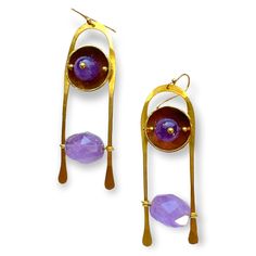 Handcrafted in brass in a simple inverted "U" shape with gemstones suspended between each side. The gemstone closest to the ear is a polished round sphere framed in a brass cup Purple Metal Drop Earrings, Purple Metal Dangle Earrings, Purple Dangle Metal Earrings, Modern Brass Earrings With Gemstones, Modern Purple Gemstone Earrings, Handmade Purple Metal Earrings, Purple Metal Earrings With Dangling Beads, Fusion Style Drop Earrings With Dangling Beads, Purple Drop Earrings With Dangling Beads