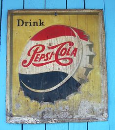 an old pepsi cola sign hanging on the side of a blue building with wood planks