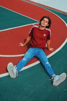 a man laying on top of a basketball court next to a green and red floor