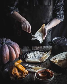 a person in an apron preparing food on top of a wooden table with pumpkins