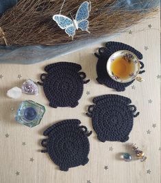 four crocheted coasters sitting on top of a table next to a cup of tea