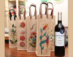 three wine bags with different designs on them next to a bottle of wine