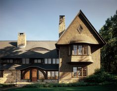 a large wooden house sitting on top of a lush green field