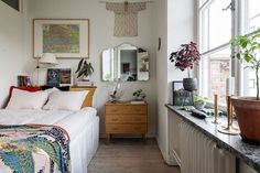 a bed room with a neatly made bed next to a window and a potted plant