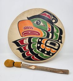 a wooden drum with an eagle painted on the side and a pipe next to it