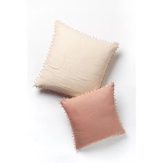 two pink and white pillows sitting next to each other on top of a white surface