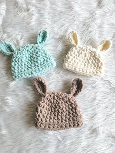 three crocheted baby hats laying on top of a white furnishing floor