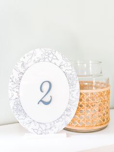 a white and blue plate with the number two on it next to a candle holder