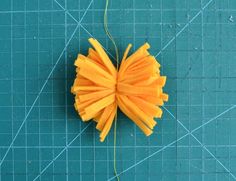 a piece of yellow paper on a cutting board with scissors and thread attached to it