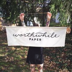 a woman holding up a sign that says worthville paper