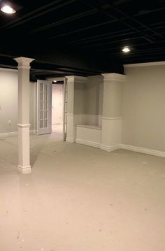 an empty room with white walls and pillars in the center is lit by recessed lights