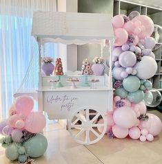 an ice cream cart decorated with balloons and pastel colors for a baby's first birthday