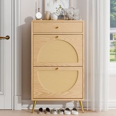 a wooden cabinet sitting next to a door with shoes on the floor and a clock above it